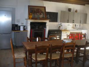 cocina con mesa de madera con sillas y chimenea en La maison de la Guérande, en Hénanbihen