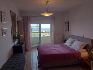 a bedroom with a bed and a window and a couch at Villa NIKITA sunrise sea view in Koskinou