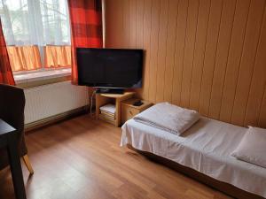 Zimmer mit einem TV, einem Bett und einem Tisch in der Unterkunft ZAJAZD KANSAS in Konstantynów Łódzki