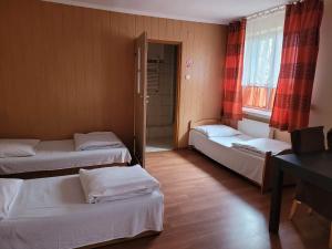 Zimmer mit 3 Betten, einem Tisch und einem Fenster in der Unterkunft ZAJAZD KANSAS in Konstantynów Łódzki