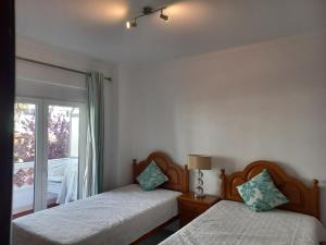 クアルテイラにあるRegueiró Quarteira Beach Apartmentのベッドルーム1室(ベッド2台付)、景色を望む窓が備わります。