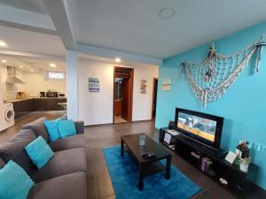 Una sala de estar con un sofá y un televisor de pantalla plana. en O Cantinho do Zé, en Funchal