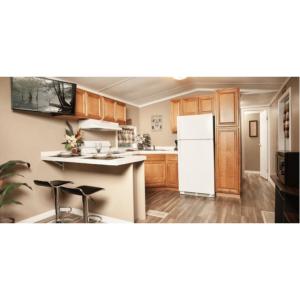 La cuisine est équipée d'un réfrigérateur blanc et de placards en bois. dans l'établissement Sunburst RV Resort, à Whitfield