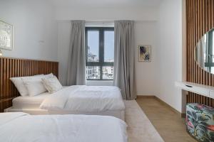 Cette chambre comprend 2 lits et une fenêtre. dans l'établissement 2 Bedroom Apartment by the beach at Port De La Mer-Dubai, à Dubaï