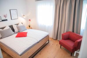 a bedroom with a bed and a red chair at Planaiblick-Lodge Schladming in Schladming
