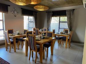 a dining room with wooden tables and chairs and windows at Allegro Guesthouse in Bloemfontein