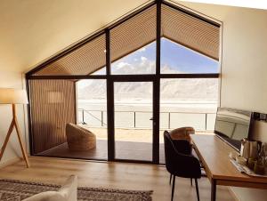 a room with a desk and a large glass window at Khoj Resorts Shigar in Shigar