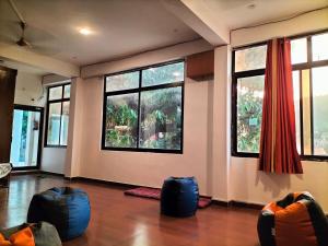 Habitación con ventanas grandes y bolsas azules en el suelo. en Sonu Guesthouse & Hostel en Rishīkesh
