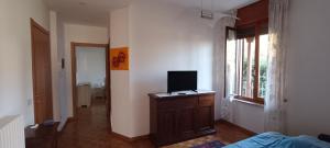 Cette chambre dispose d'une télévision sur une commode en bois et d'une fenêtre. dans l'établissement A casa di Mirco, à Viverone