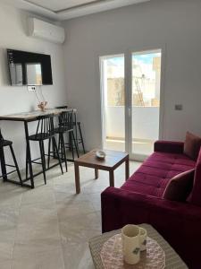 a living room with a purple couch and a table at Studio Rouge Cosy à Dar Lili Djerba in Mezraya