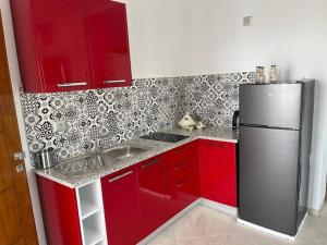 a kitchen with red cabinets and a stainless steel refrigerator at Studio Rouge Cosy à Dar Lili Djerba in Mezraya
