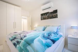 um quarto branco com uma cama com um cobertor azul em Apartman Pascal em Porec