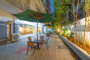 a table and chairs with a green umbrella on a sidewalk at Hotel Athome , Whitefields, Kondapur in Hyderabad