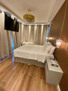 a bedroom with a bed and a table and a television at Navega Beach Palace Hotel in Navegantes