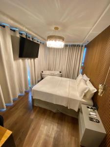 1 dormitorio con 1 cama blanca grande y TV en Navega Beach Palace Hotel, en Navegantes