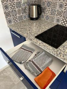 a kitchen counter with a shelf with several dishes and towels at Studio Bleu Cosy à Dar Lili Djerba in Mezraya