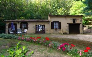 une petite maison avec des fleurs devant elle dans l'établissement Roquecombe, à La Roque-Gageac