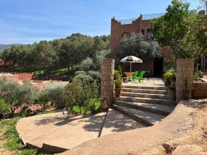 una casa con scale e un tavolo e un ombrello di Maison d´hôtes Amazir a Ouzoud