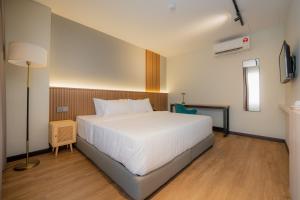 um quarto com uma cama branca e um candeeiro em Matata Hotel Kota Kinabalu em Kota Kinabalu