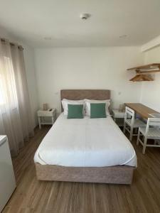 a bedroom with a large bed and a table at Alojamento Sudoeste in Zambujeira do Mar
