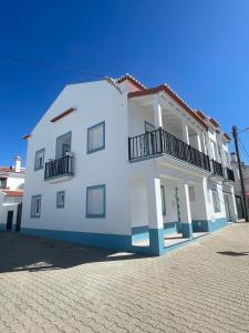 - un bâtiment blanc avec des balcons sur le côté dans l'établissement Alojamento Sudoeste, à Zambujeira do Mar