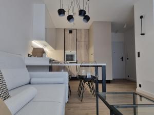 a living room with a white couch and a glass table at Fuzja Ana - Garaż - Klimatyzacja - Dostęp na Kod - FV in Łódź