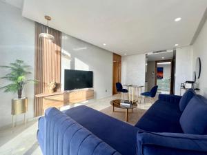 uma sala de estar com um sofá azul e uma televisão em ZEN Suites Hotel Massira em Casablanca