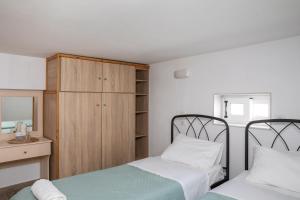 a bedroom with two beds and a wooden cabinet at Melina's House 2 in Kardamaina