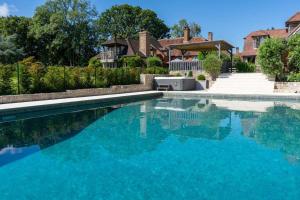 una piscina con acqua blu in una casa di Lickfold Manor - Luxury home with swimming pool a Lurgashall