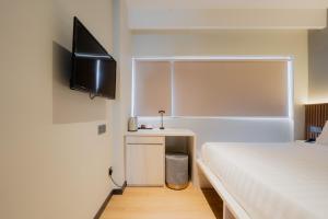 a bedroom with a bed and a flat screen tv at Matata Hotel Kota Kinabalu in Kota Kinabalu