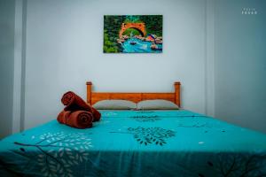 una cama con un edredón azul y una pintura en la pared en Hotel Athina & Restaurant en Chilaw