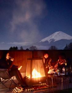 un grupo de personas sentadas alrededor de un fuego con una montaña en el fondo en ヴィラ山間堂 Terrace Villa BBQ Bonfire Fuji view Annovillas en Fujikawaguchiko