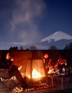 a group of people sitting around a fire with a mountain in the background at ヴィラ山間堂 Terrace Villa BBQ Bonfire Fuji view Annovillas in Fujikawaguchiko
