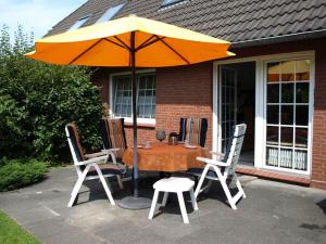 einen Tisch und Stühle mit Sonnenschirm auf einer Terrasse in der Unterkunft *Weigelt - Ferienwohnung Issy in Greetsiel