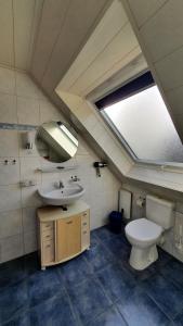 ein Badezimmer mit einem WC, einem Waschbecken und einem Spiegel in der Unterkunft *Weigelt - Ferienwohnung Issy in Greetsiel