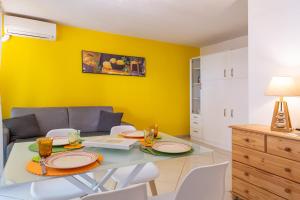 jadalnia ze stołem i krzesłami oraz żółtą ścianą w obiekcie Studio St Jean à Roquebrune, proche Menton et Monaco w mieście Roquebrune-Cap-Martin