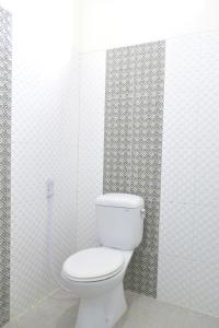 uma casa de banho com um WC numa parede de azulejos brancos em The Cabin Hotel Ambasador em Yogyakarta