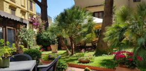 um jardim com palmeiras, uma mesa e cadeiras em Green Hotel em Roma
