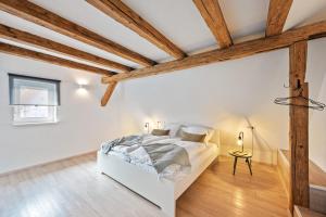 1 dormitorio con paredes blancas y vigas de madera en Sali Homes- Penthouse en Obersulm
