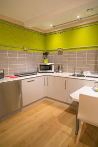 a kitchen with white cabinets and a yellow wall at Claron Lodge in West Wittering