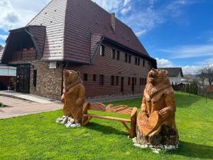 Piatra Soimului في فيشو دي سوس: اثنين من تماثيل الدببة جالسين على مقاعد امام المبنى