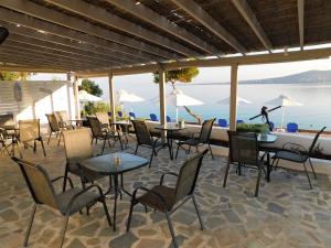 a patio with tables and chairs and a view of the water at Perdika Mare Guesthouse in Perdika
