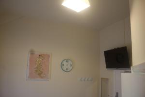 una habitación con reloj y TV en la pared en Elm Tree Guest House, en Weston-super-Mare