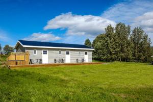 a white house with a blue roof on a green field at Vallakot Farm Guesthouse in Laugar