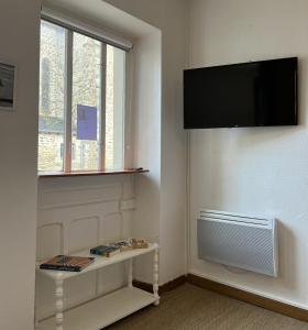 um quarto com uma televisão na parede e uma mesa em HOTEL KAN AVEL em Saint-Lunaire