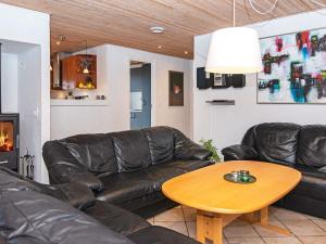 a living room with a leather couch and a table at 12 person holiday home in Ulfborg in Husby