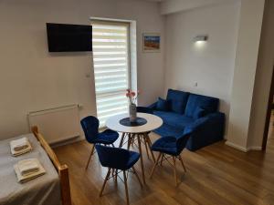 a living room with a blue couch and a table at Apartamenty Bełska Centrum in Ustrzyki Dolne