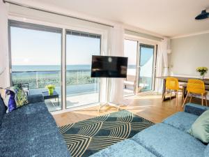 a living room with a blue couch and a large window at Dreamcatcher in South Hayling