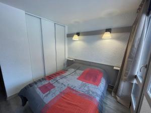 a small bedroom with a bed with a red blanket at Appartement Plagne 1800, 2 pièces, 4 personnes - FR-1-181-2708 in La Plagne Tarentaise