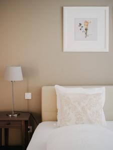 a bed with a white pillow and a picture on the wall at Appartement Meyer-Ernzen in Echternach